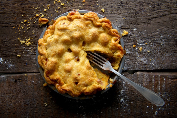 Apple Pie on Rustic Wooden Background with Fork and Crumbs