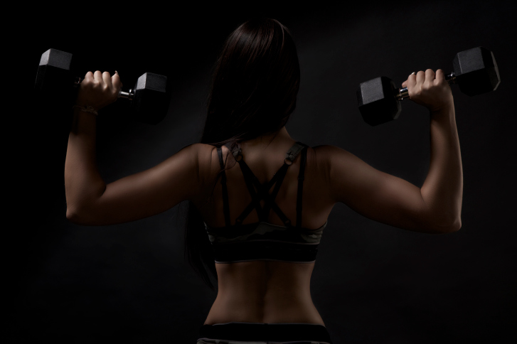 back profile of woman with weights in both hands