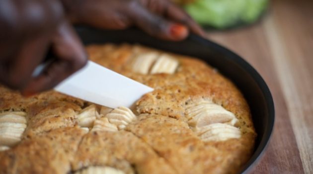 African American Black Woman is cutting a piece of apple cake