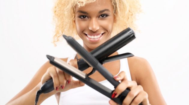 African American woman holding curling iron and flat iron