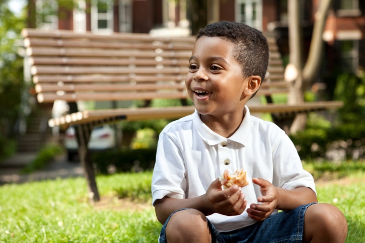 little boy eating in the park