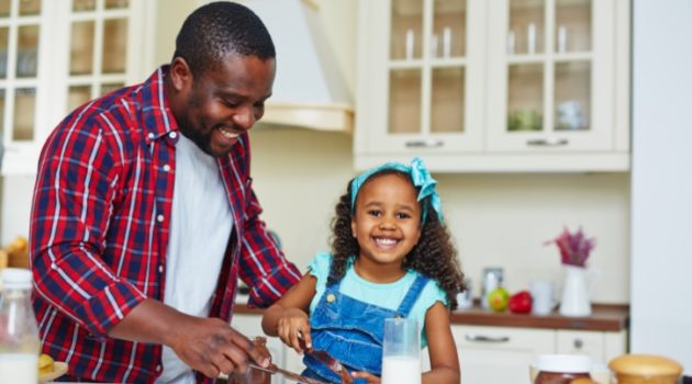 African American Black father and daughter making sandwich in kitchen