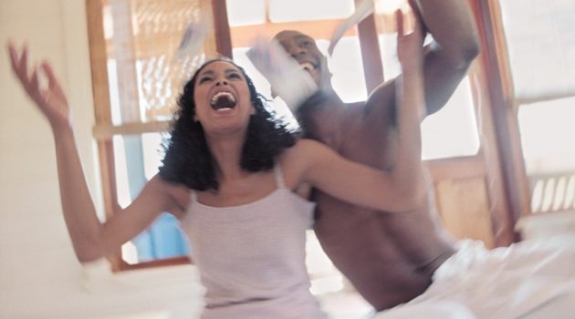 African Americancouple in bed throwing money in the air