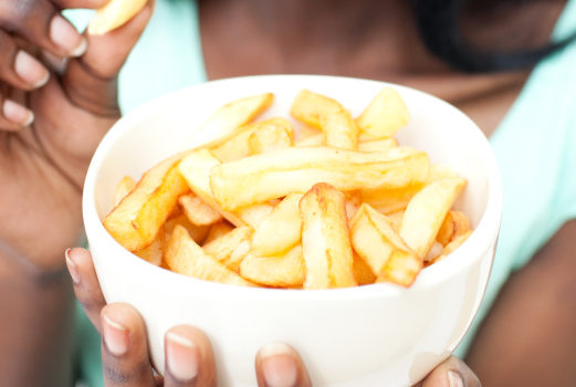 African American teen girl eating bowl of fries