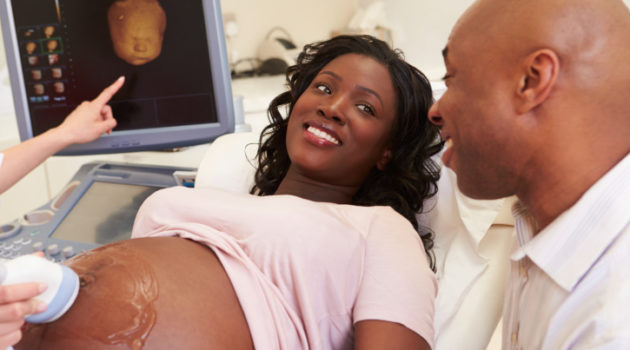 African American pregnant woman and man getting ultrasound at doctor office