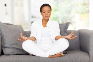 African American woman meditating on couch