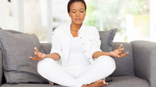 African American woman meditating on couch