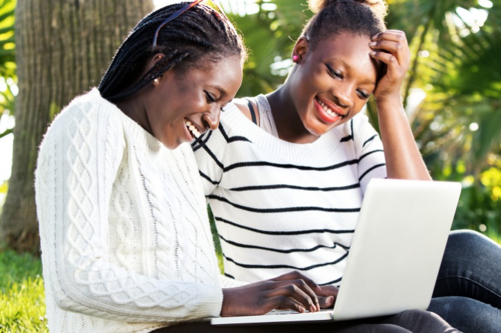 African American teen girls on laptop outside