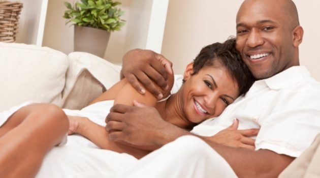 Happy African American couple hugging on couch