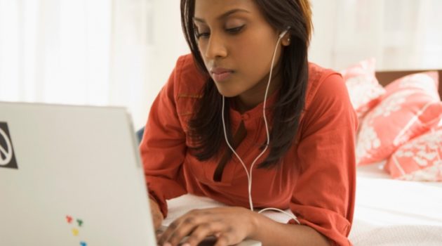 African American woman on laptop with headphones earbuds