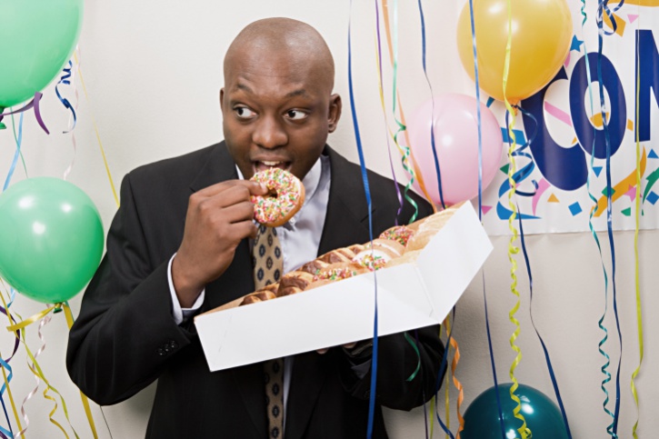 African American man secretly eating box of donuts