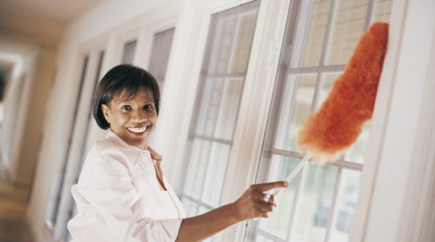 African American woman dusting home windows