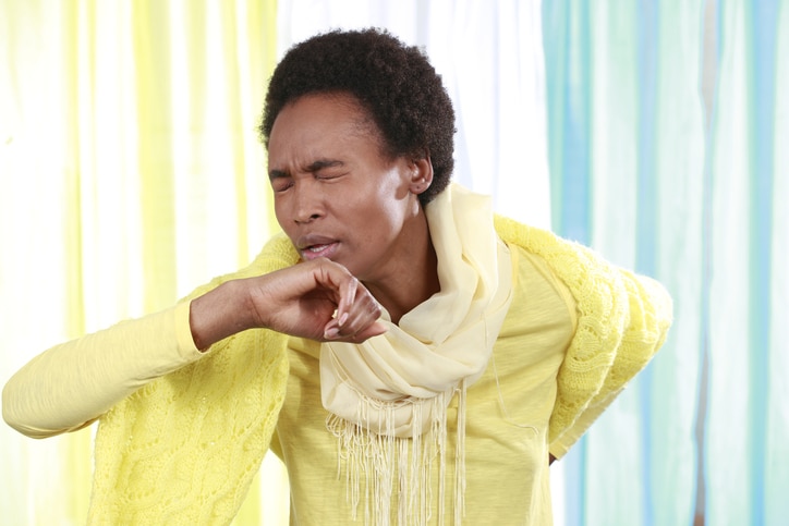 African woman with scarf coughing