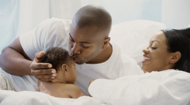 African American family in bed with baby