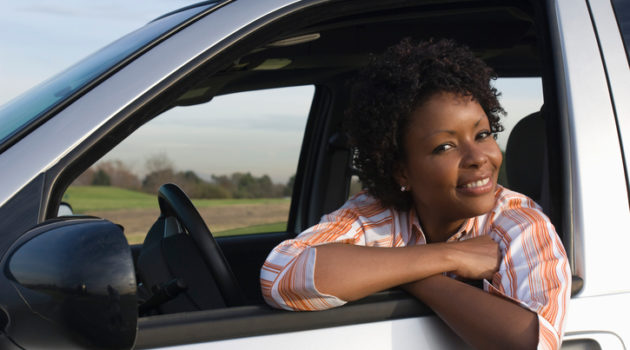 African American woman leaning out car window smiling