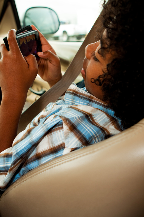 African American child playing video game in car