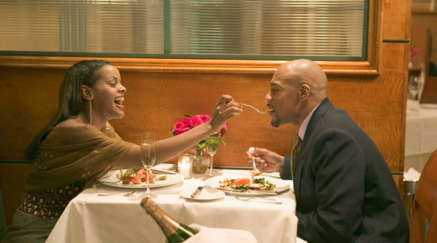 African American couple on date feeding each other