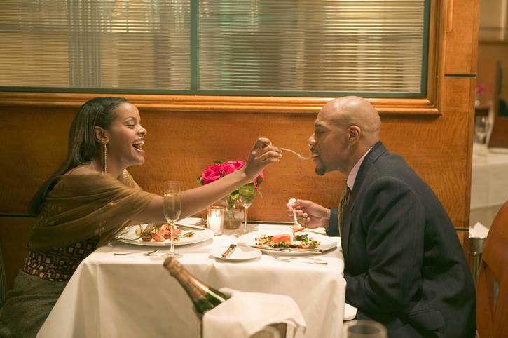 African American couple on date feeding each other