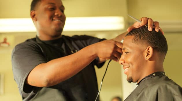 African American man getting hair cut at barbershop
