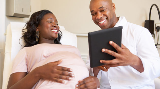 African American woman pregnant talking to doctor