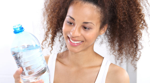 African American woman drinking water bottle