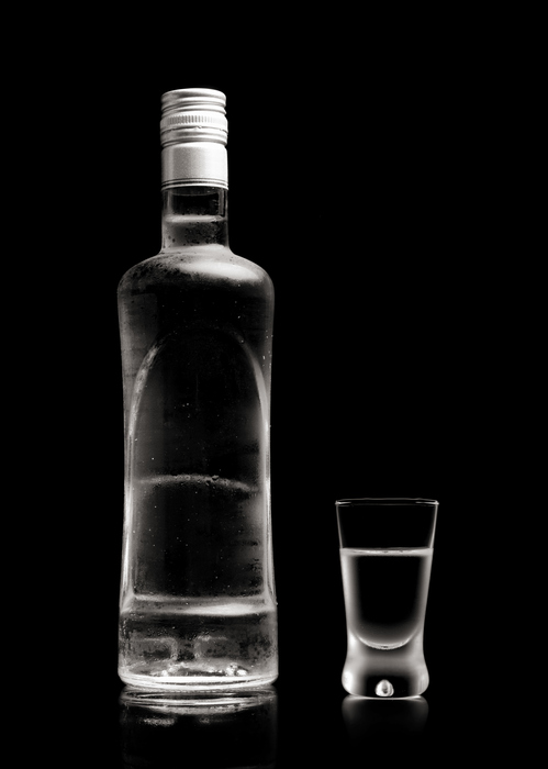 Close-up view of bottle and glass standing of vodka isolated on black