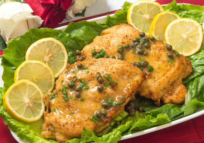 chicken piccata on a table with fresh roses