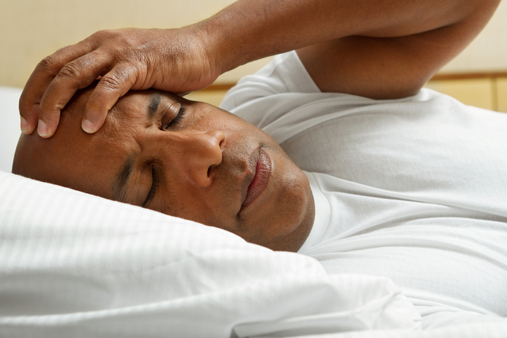 African American man in bed insomnia headache