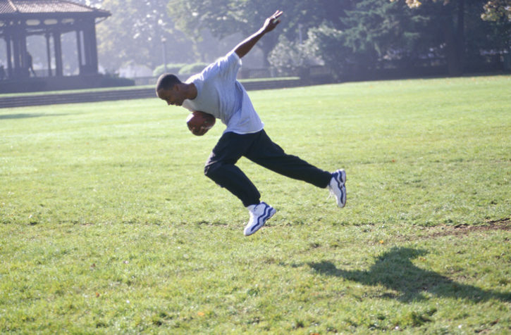 African American teen boy running with football