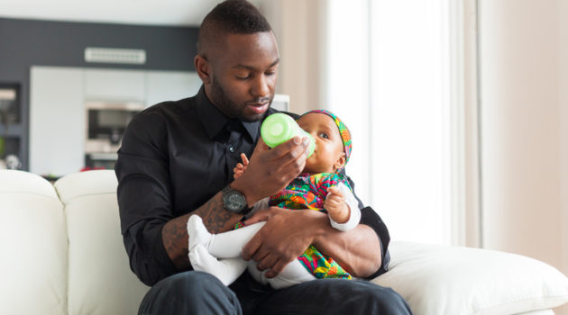 African American father feeding baby girl bottle