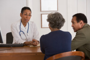 African American woman doctor speaking with couple