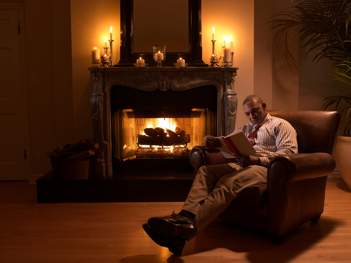 Senior African American man reading by fireplace
