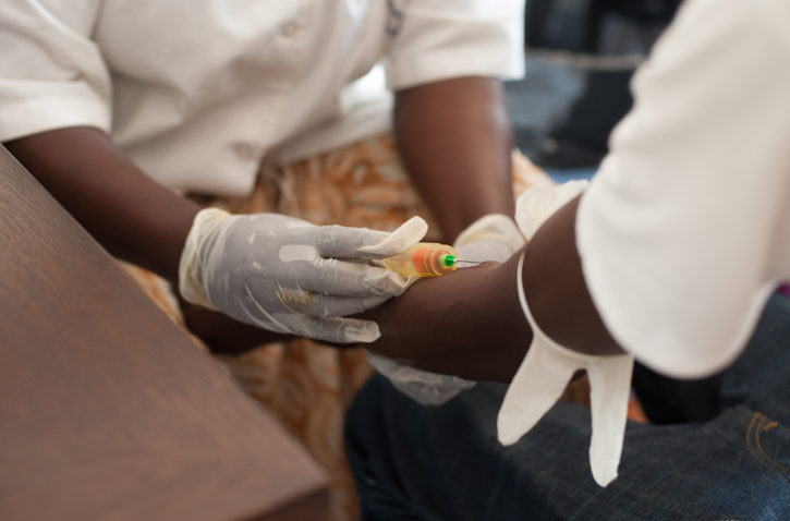 African American nurse draws blood needle