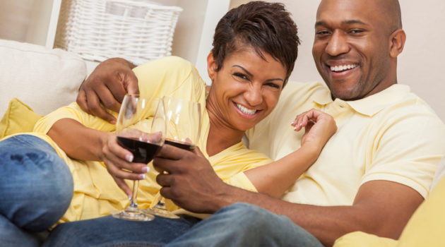 African American couple drinking wine on couch