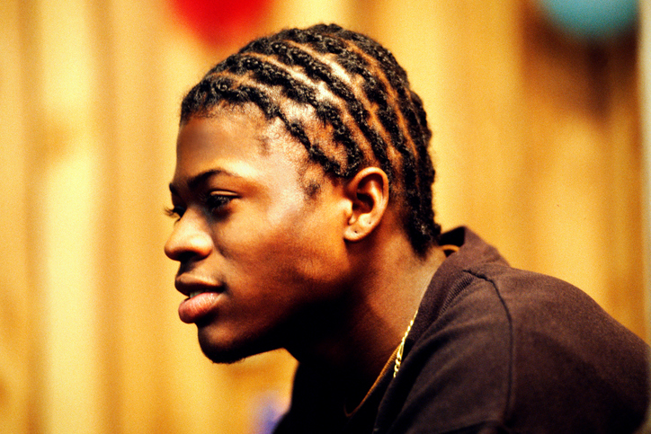 Side view portrait of a young man with braided hair.