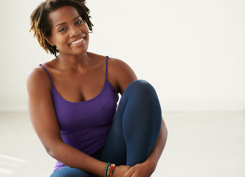 Happy African American woman exercising on yoga mat