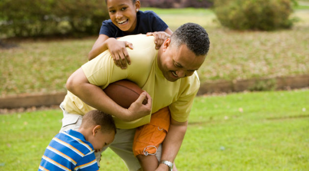 African American father playing outside with children