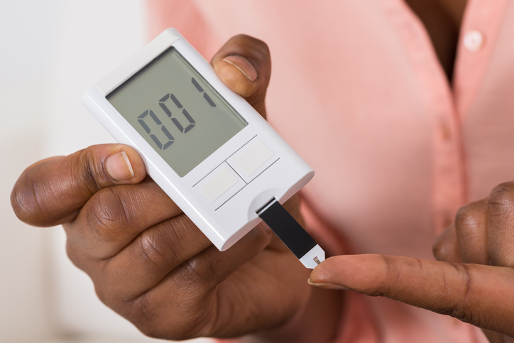 African American holding diabetes glucose meter with test strip