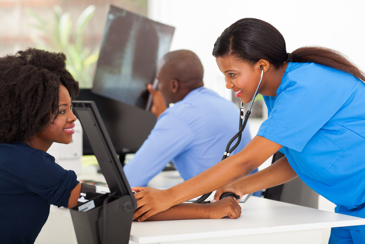 African American nurse taking woman's blood pressure