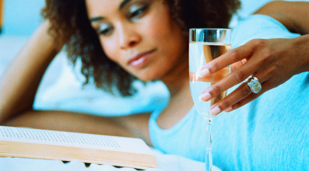 African American woman drinking wine reading