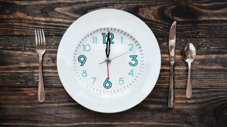 Twelve hour intermittent fasting time concept with clock on plate.