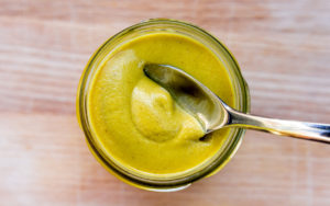 Mustard in a cup with spoon. 