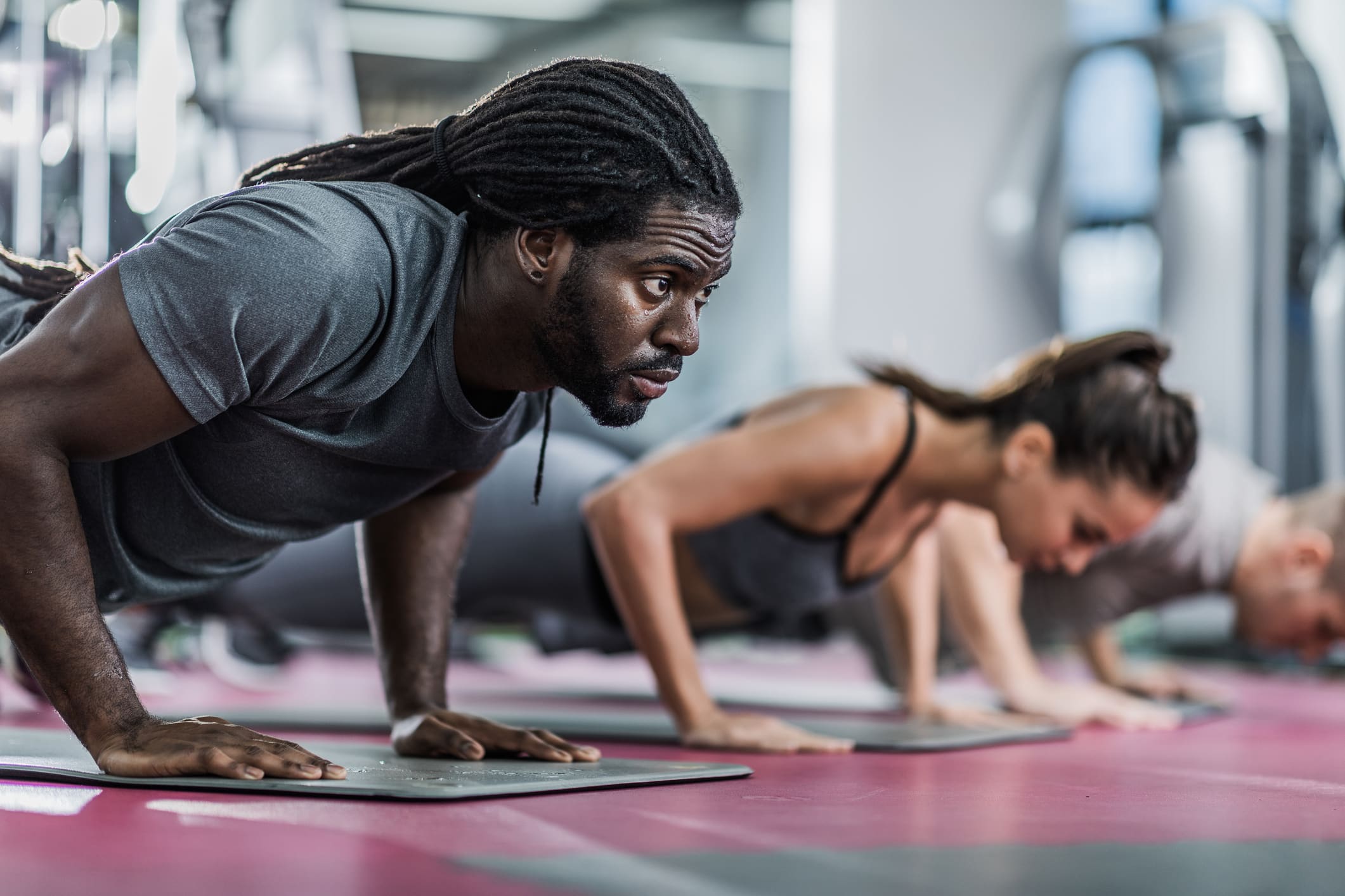 Group of athletes exercising push-ups in a health club. - BlackDoctor