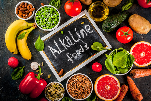Healthy food background, trendy Alkaline diet products - fruits, vegetables, cereals, nuts. oils, dark blue concrete background above