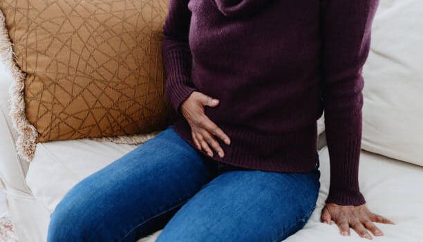 a person sitting on a couch holding her stomach